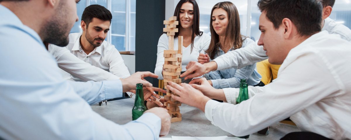 Ya casi se cae. Celebrando el trato exitoso. Jóvenes oficinistas sentados cerca de la mesa con alcohol