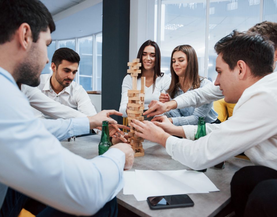 Ya casi se cae. Celebrando el trato exitoso. Jóvenes oficinistas sentados cerca de la mesa con alcohol