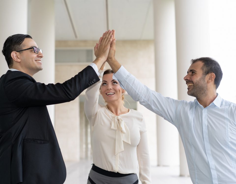 Gente de negocios alegre dando un alto cinco para celebrar el éxito