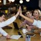 Vista lateral de personas chocando los cinco durante una reunión de oficina