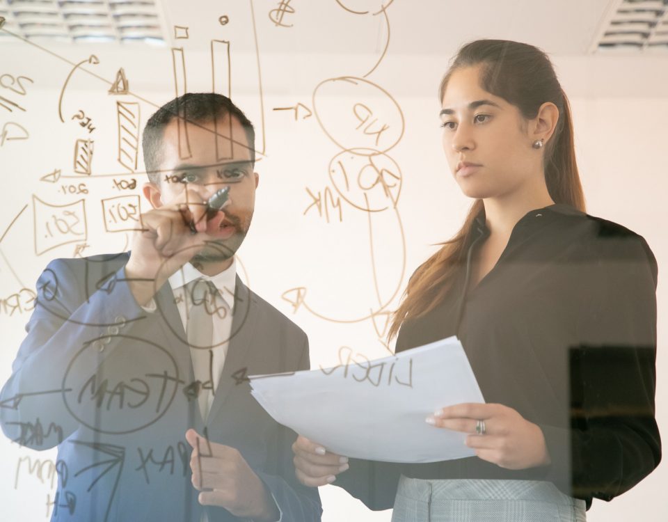 Contenido administrador afroamericano escribir gráfico sobre placa de vidrio. Colega bastante femenina joven profesional que sostiene el documento y que mira el gráfico en la sala de conferencias. Concepto de marketing y trabajo en equipo